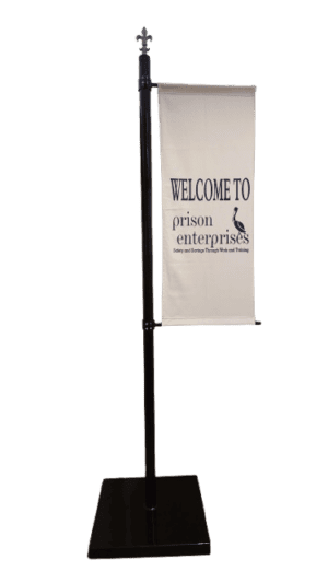 An 8-Foot Vertical Banner Pole with a black stand displays "Welcome to prison enterprises" and a bird graphic above small text.