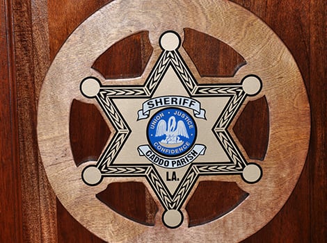A wooden plaque with a six-pointed sheriff badge for Caddo Parish, Louisiana, featuring a pelican and the words "Union, Justice, Confidence.