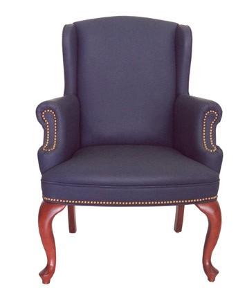 The PE Wingback Guest Chair features navy blue fabric, wooden legs, and brass nailhead trim on the arms and seat.