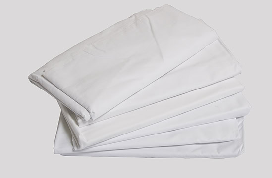 Five Muslin Sheets 54x104, neatly folded and stacked against a plain, light background.